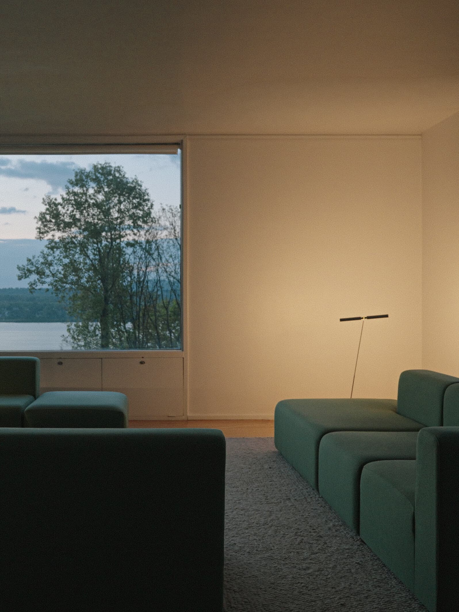 Ramulus glowing across a living room at Wolf House, lake view through the window at dusk
